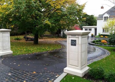 Formal entrance posts with asphalt and paver driveway